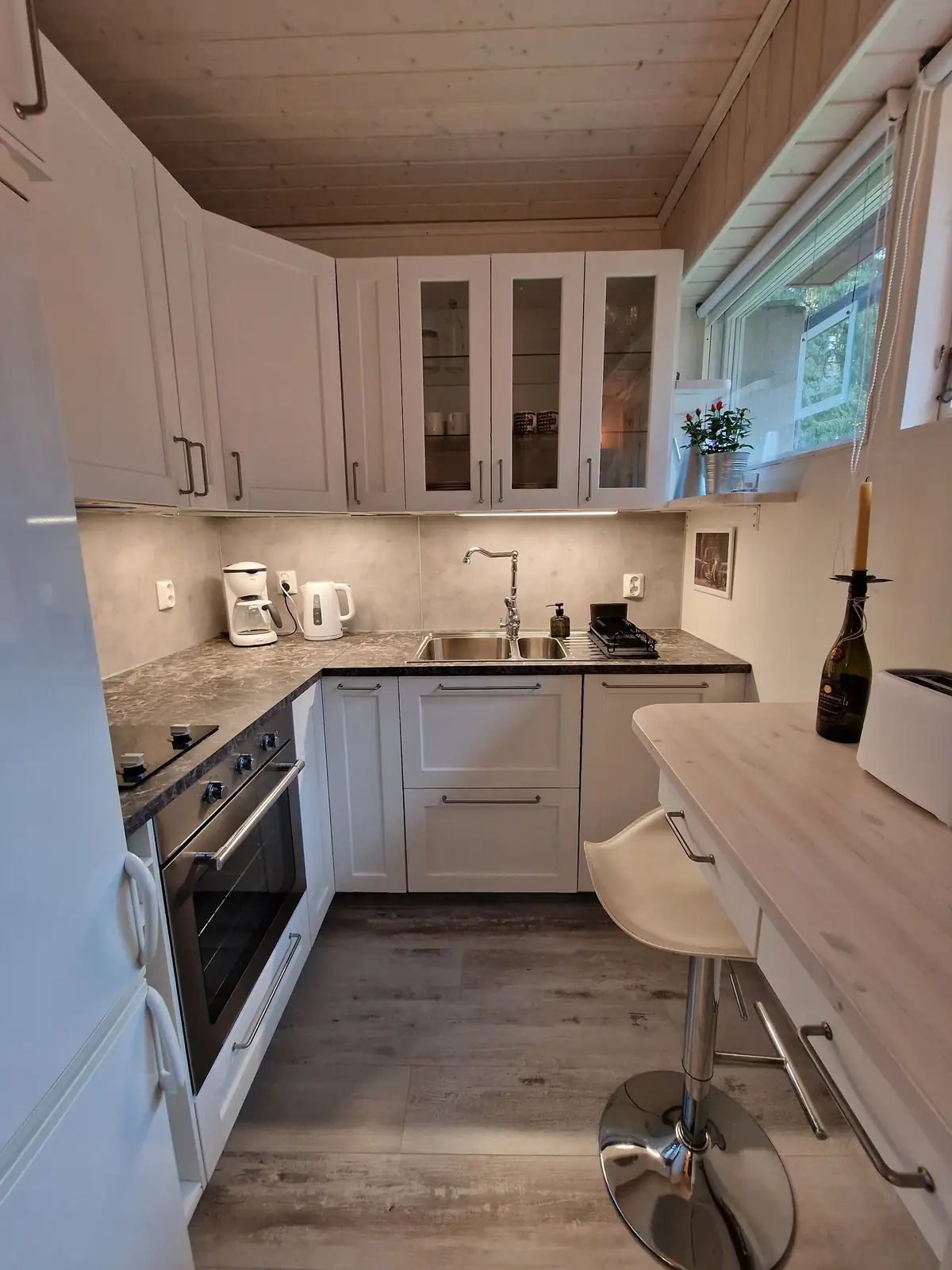 Kitchen with dishwasher, oven, hob and fridge freezer, and bar stool and desk